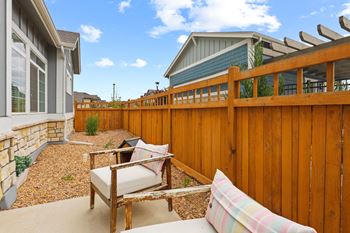 A backyard with a wooden fence and patio furniture